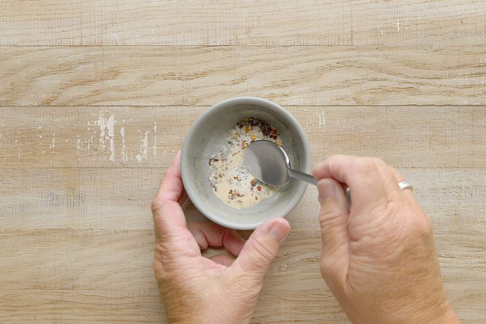 Combining seasoning into a mixture in a small bowl with a spoon