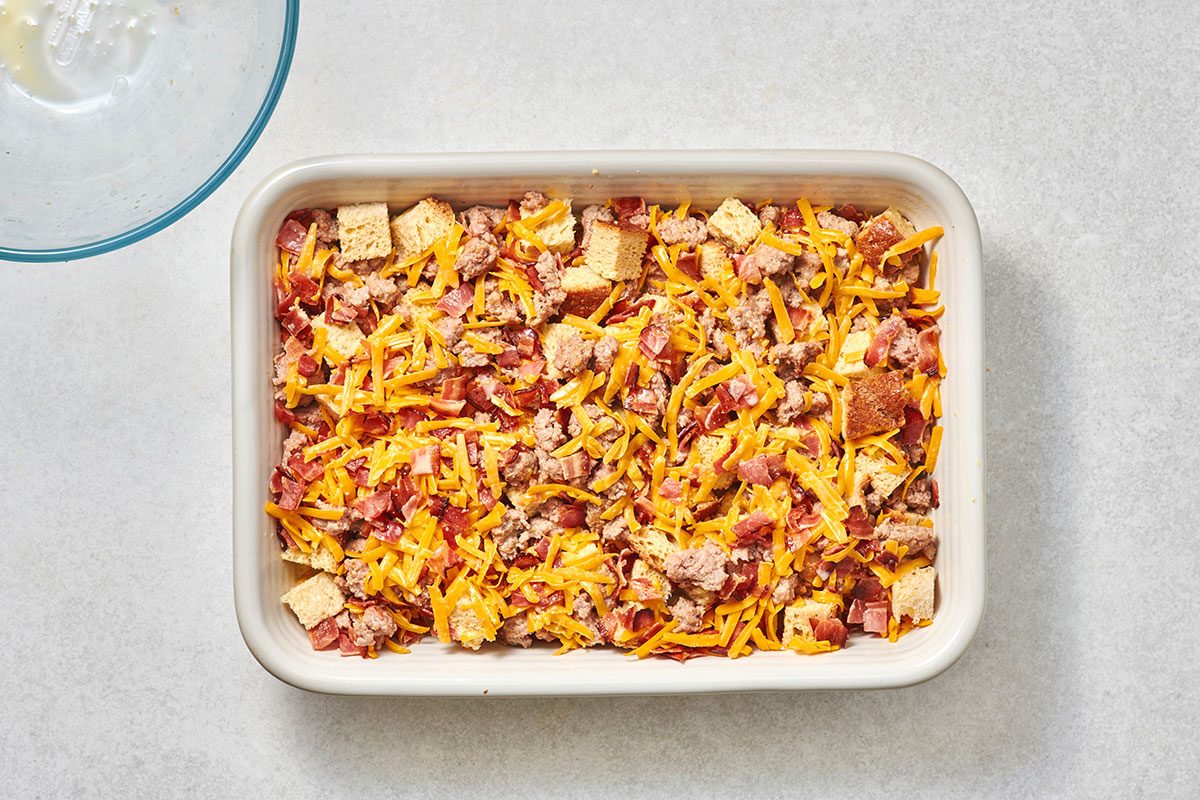 Adding the remaining ingredients over the sausages and bread