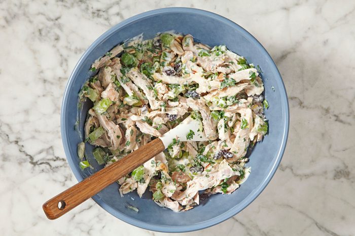 shredded cooked chicken, celery, green onion, parsley, raisins and almonds stirred and combined together in a bowl
