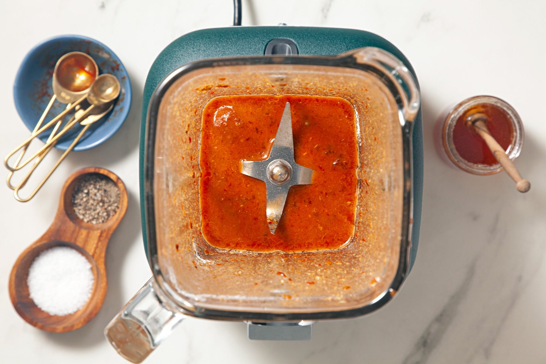 A blender filled with a mixture of ingredients, placed on a marble countertop.