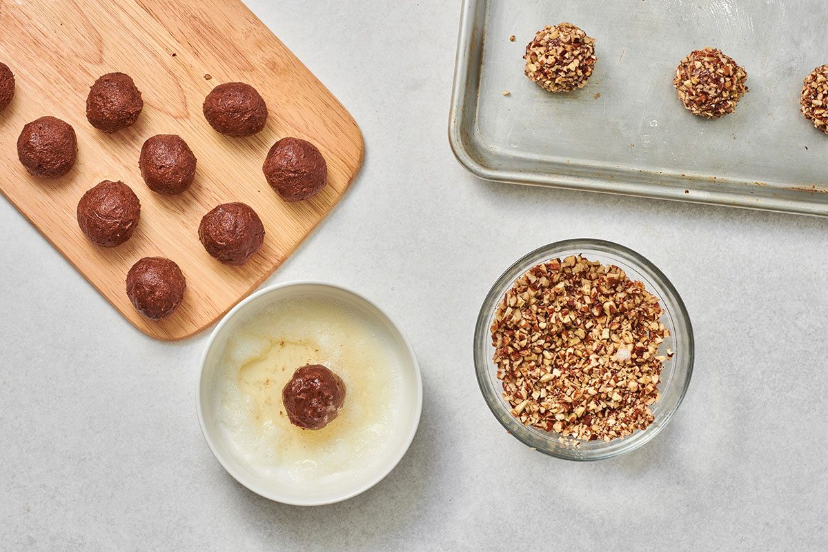 Dipping each dough ball in egg white, then rolling in pecans and pressing gently to help them adhere