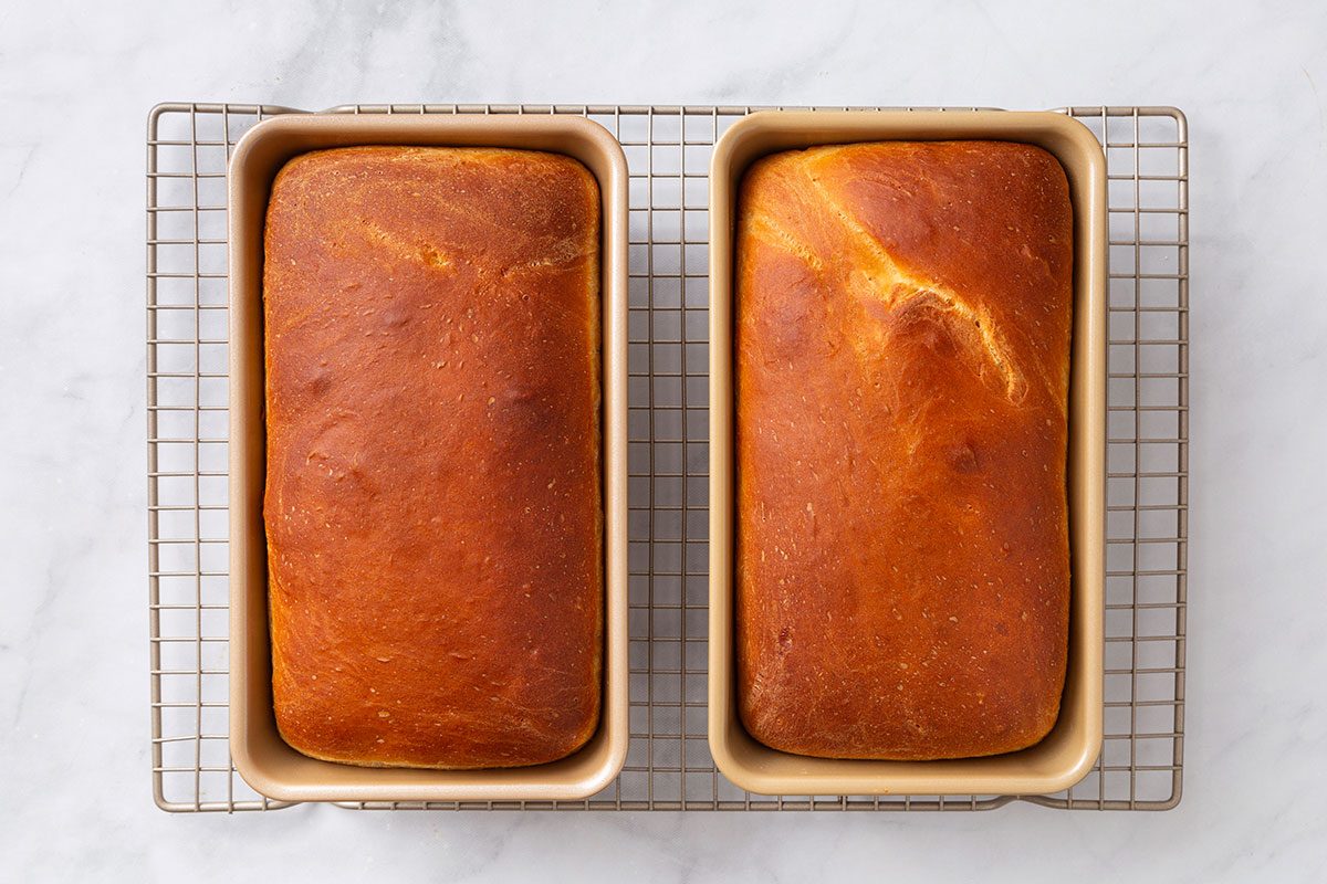 Baked bread loaves cooling on a wire rack for step four of Country White Bread recipe for Taste of Home