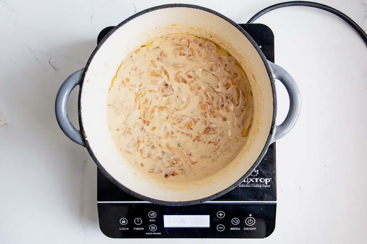 Overhead shot for Taste of Home Creamed Onions, milk and onion mixture cooking in a dutch oven.