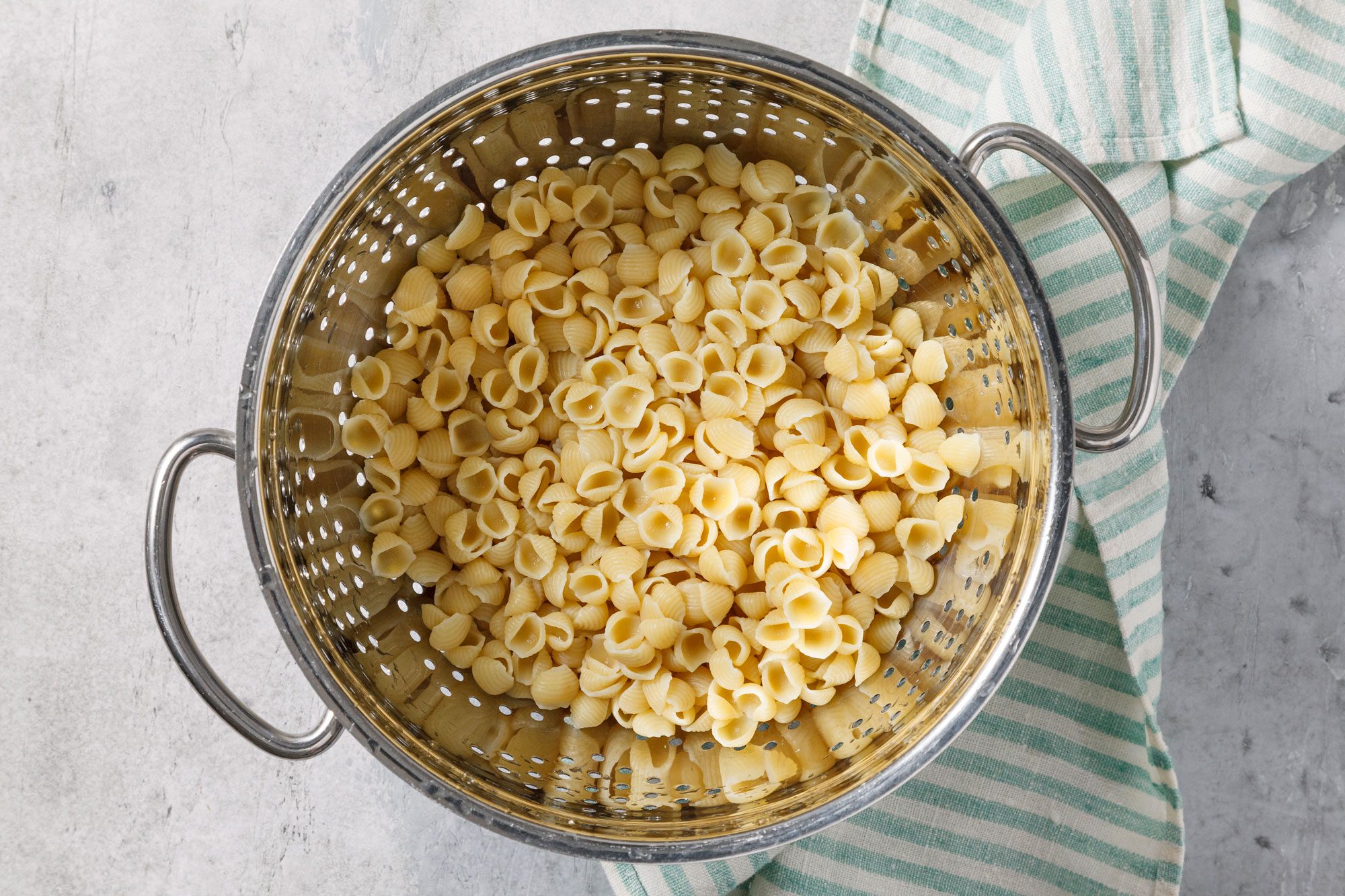 Overhead shot of cook pasta according to package directions; drain; rinse with cold water and drain again; napkin; grey surface;