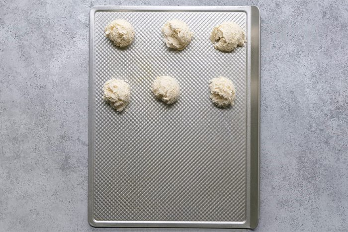 Overhead shot of drop by 1/4 cupfuls 1 inch apart onto greased baking sheets; bake until bottoms are golden brown; 17-20 minutes; Serve warm; grey surface;
