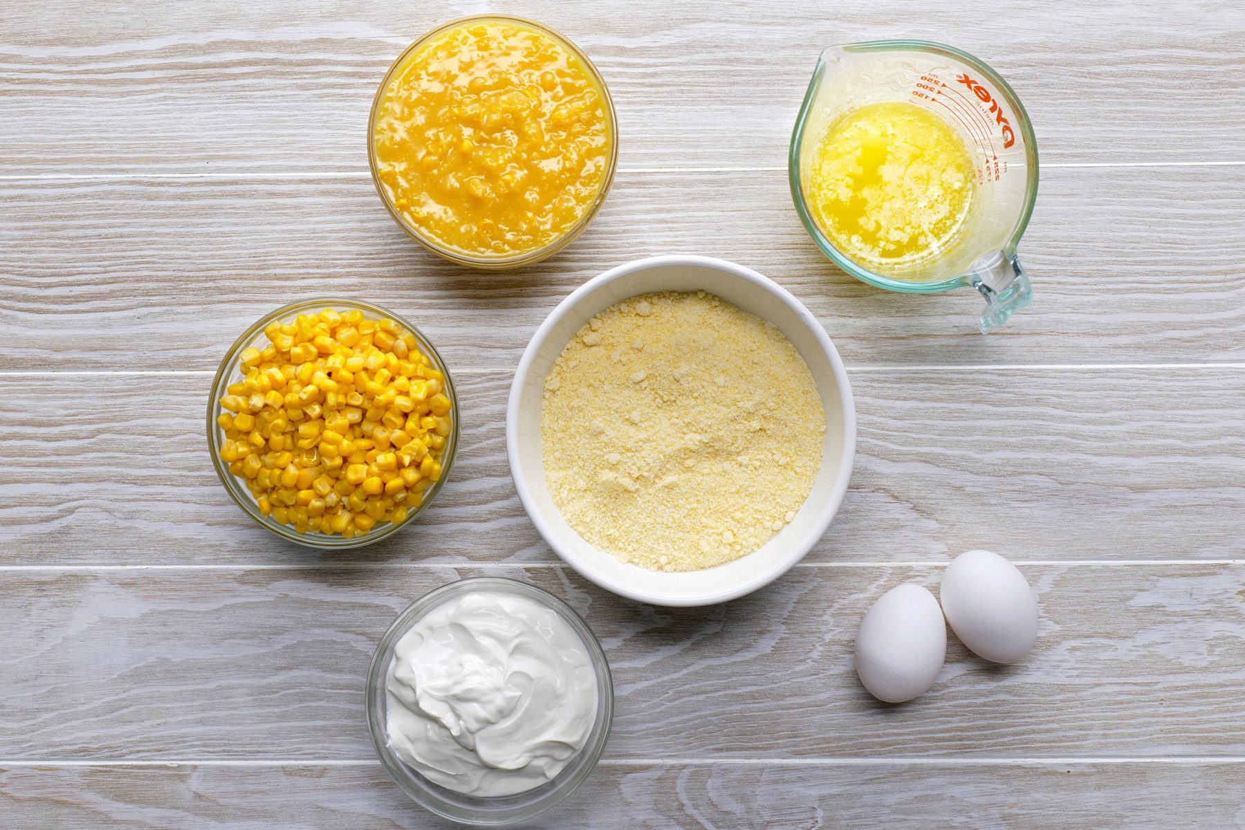 overhead shot of Easy Corn Casserole ingredients placed over wooden background;
