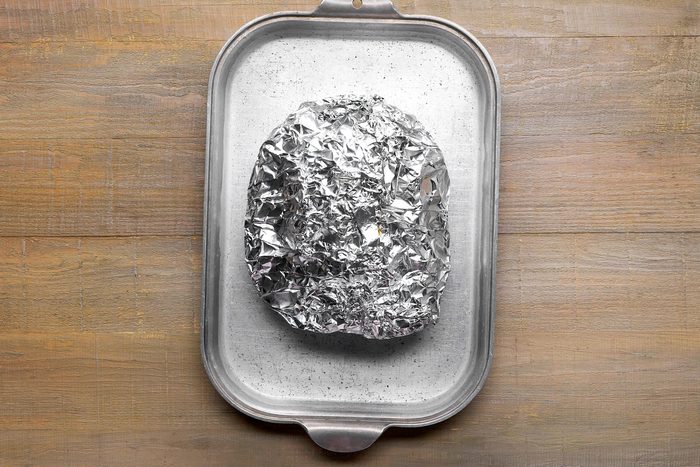 Pork meat wrapped in foil and placed on a shallow baking pan