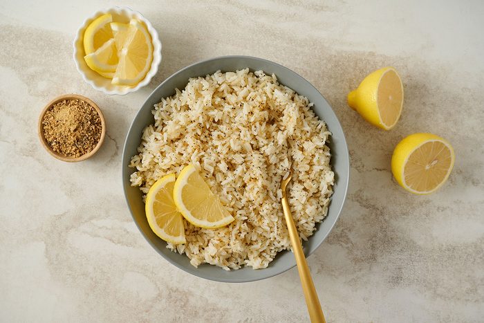 Overhead view of the finished Taste of Home Lemon Rice, garnished with lemon wedeges and lemon-pepper seasoning in a serving bowl.