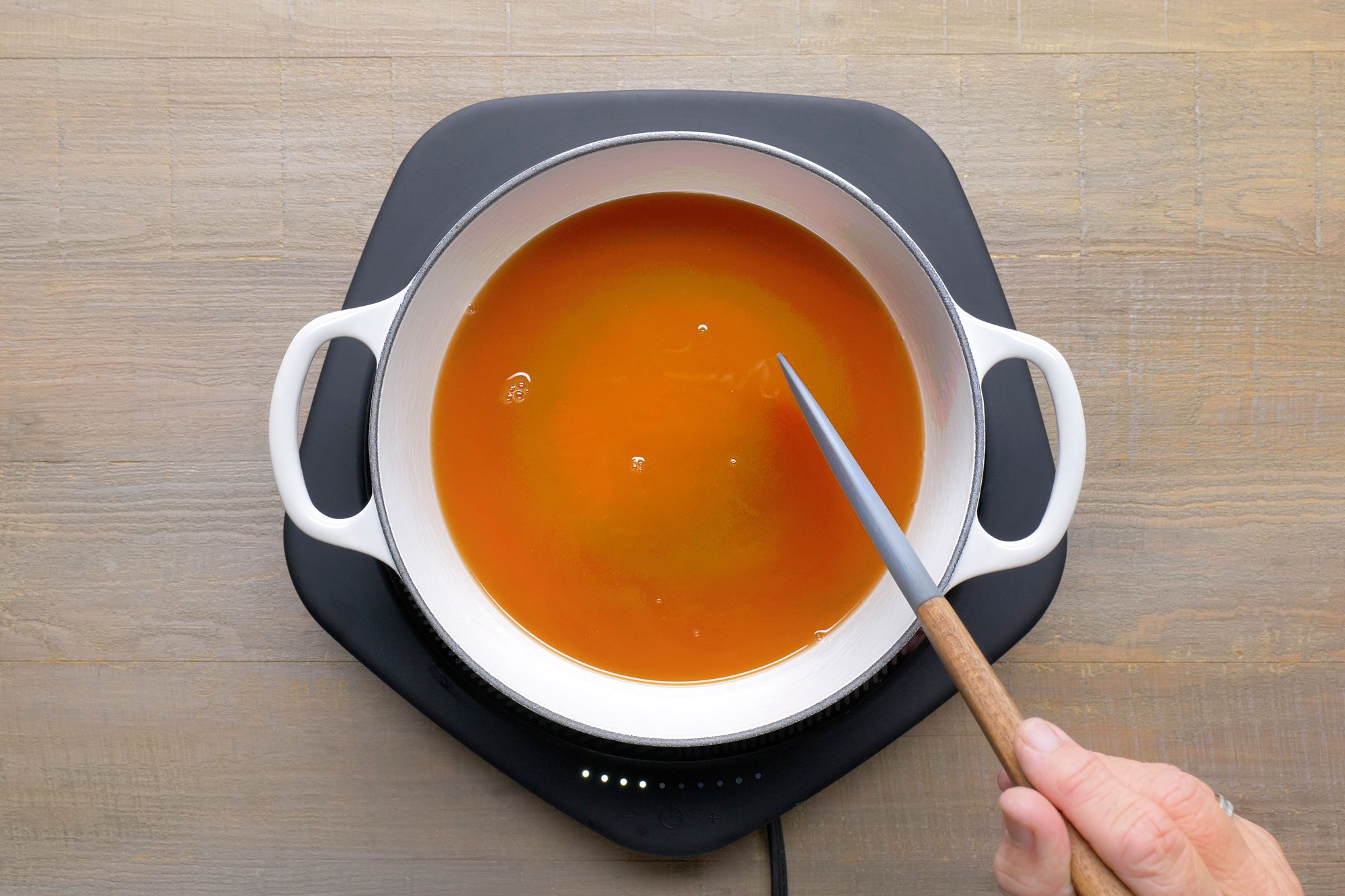 Overhead shot of a dutch oven or stock pot; spatula; induction; wooden surface;