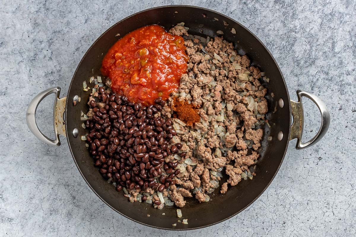 Taste of Home Nacho Casserole photo of the beans, picante sauce, and chili powder added to the skillet.