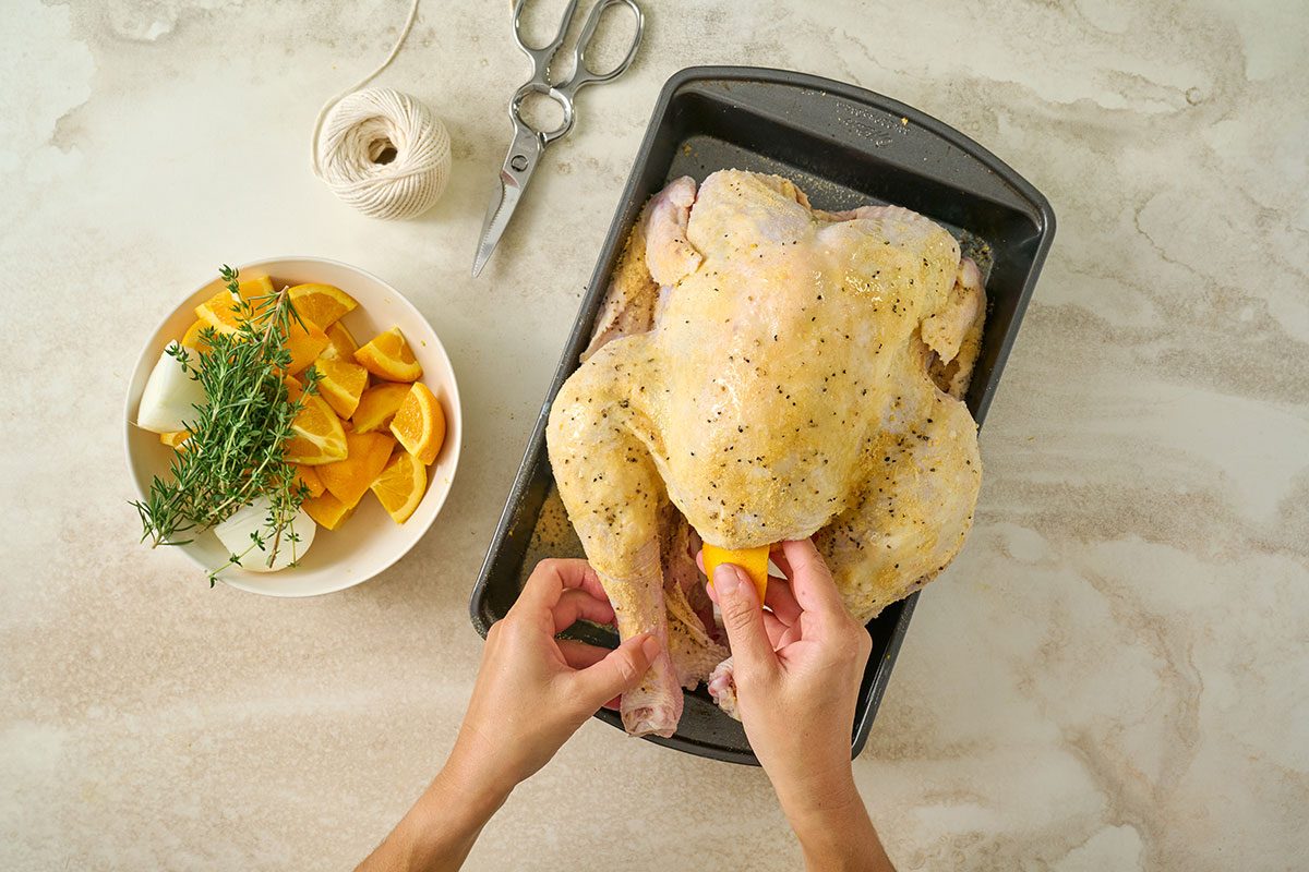 Overhead view of the turkey being patted dry and seasoned with garlic powder, salt, and pepper on the outside for the Taste of Home Orange Turkey recipe.