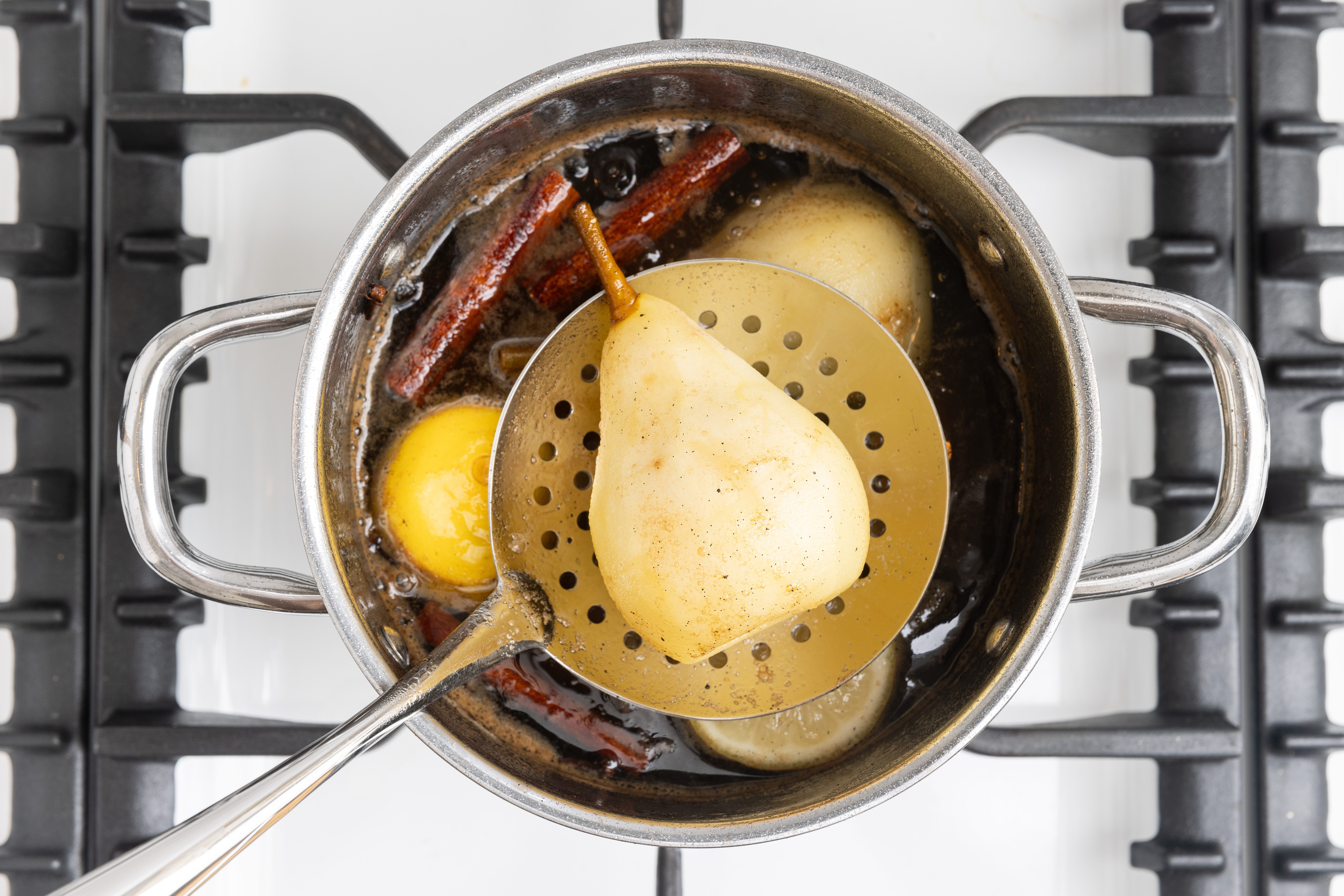Pears being removed with slotted spoon.