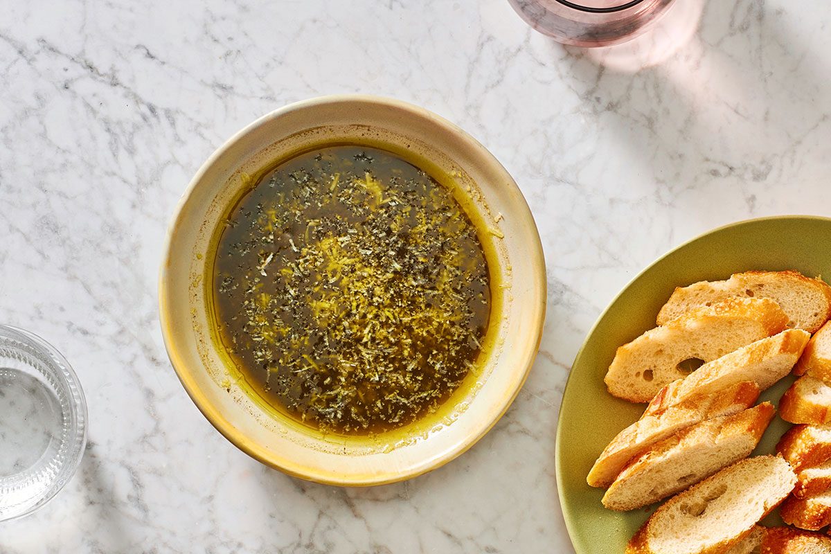 Pesto dipping oil in a shallow serving bowl, served with sliced baguette