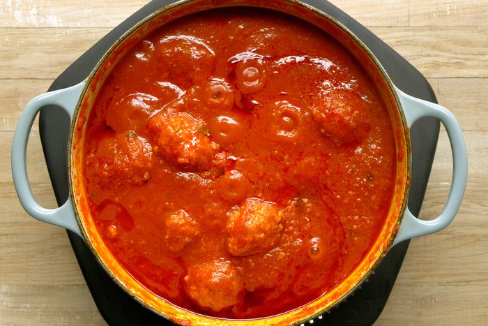 Adding raw meatballs to the simmering sauce. Bring to a simmer and cook.