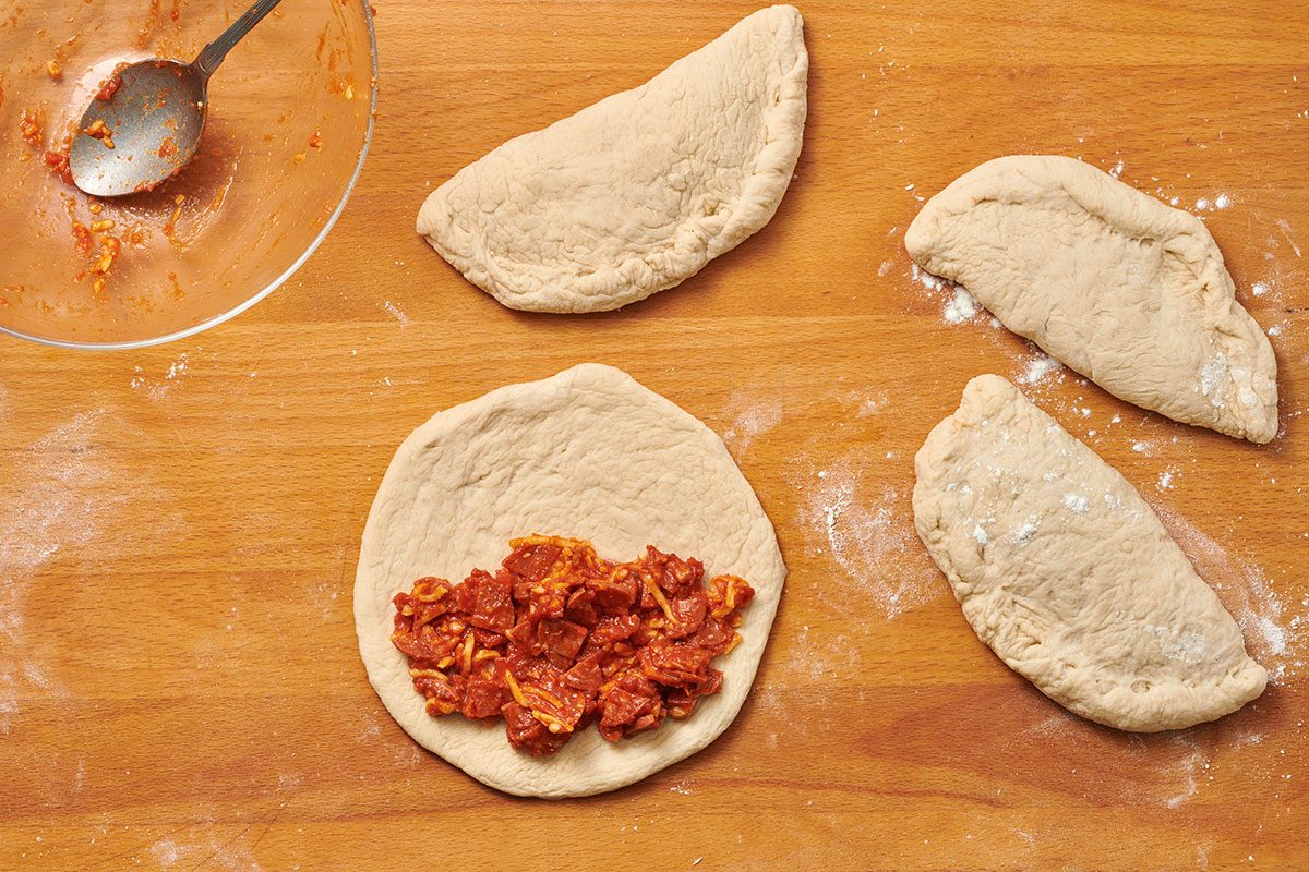 Forming calzones on a cutting board, with one left open