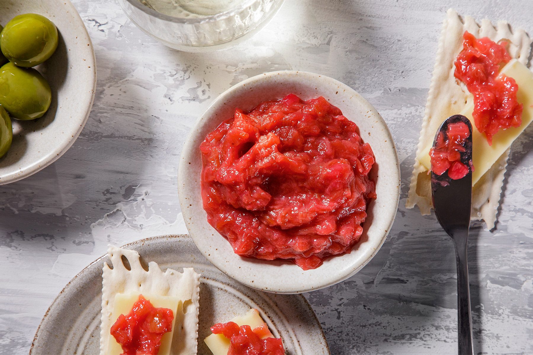 Overhead shot of Rhubarb Compote; serve in a bowl; with snacks; knife; grey surface;