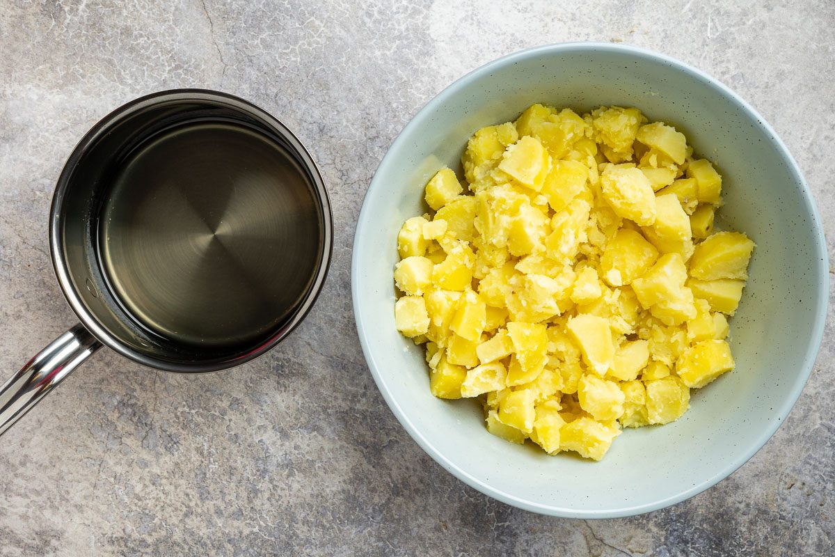 Taste of Home Russian Potato Salad recipe photo of the cooked potatoes in a bowl topped with sugar and vinegar mixture.
