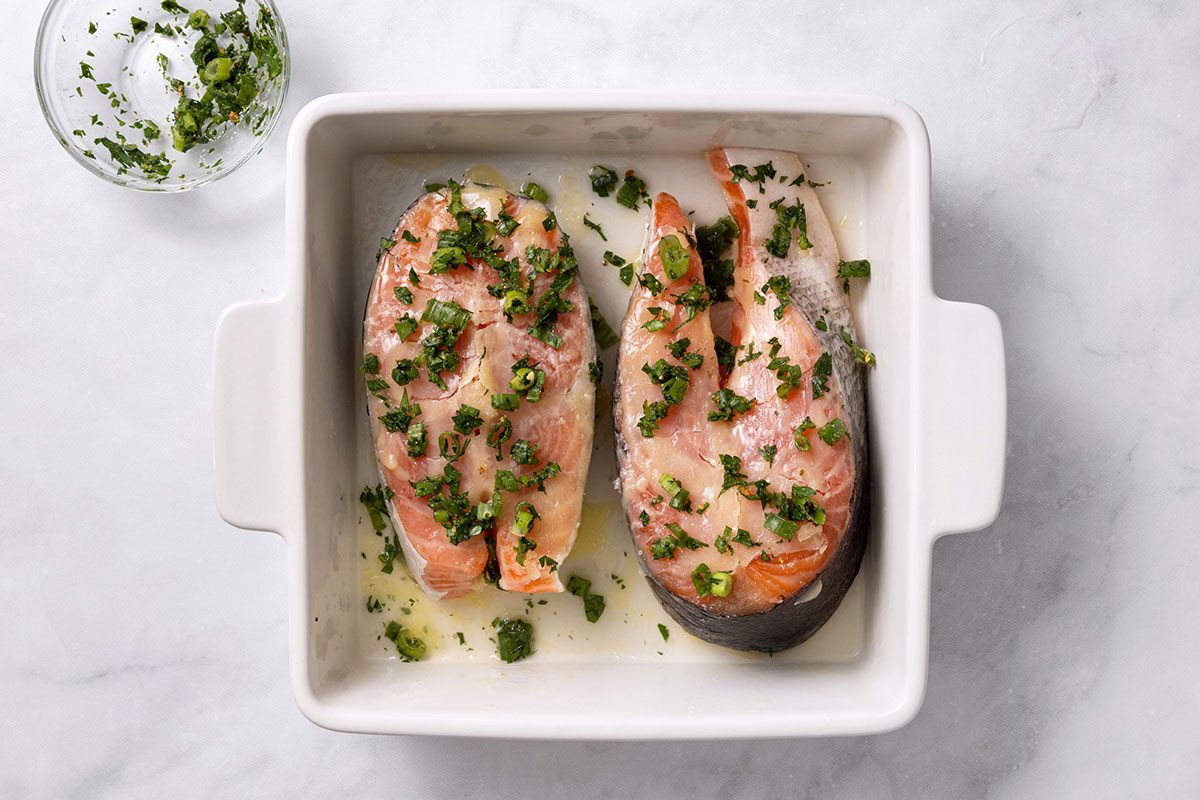 Salmon steaks seasoned with sliced green onion, minced parsley, garlic salt and lemon-pepper seasoning for step three of Salmon Steak recipe for Taste of Home