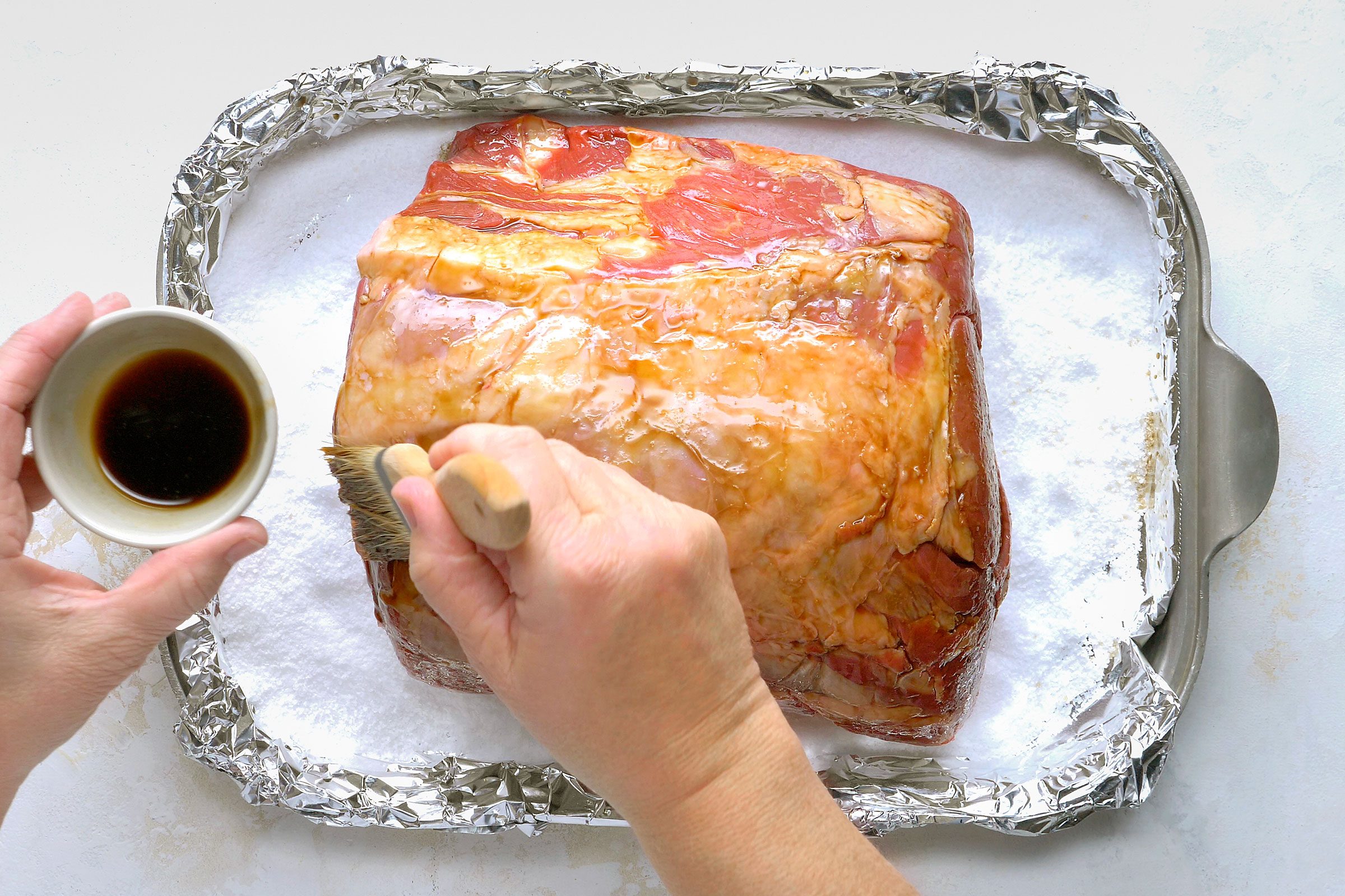Brushing rib roast with Worcestershire sauce.