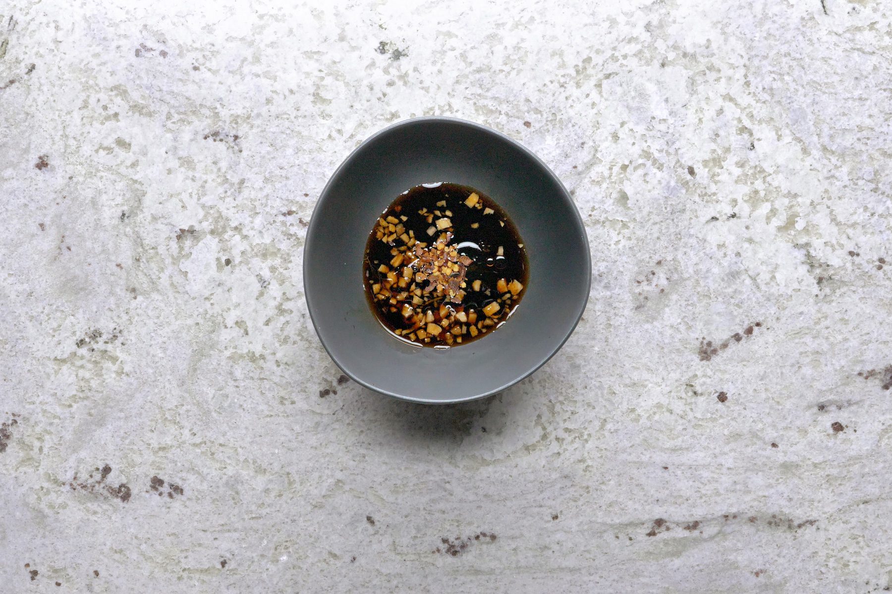Mixing soy sauce, brown sugar, ginger, rice vinegar, sesame oil, and red pepper flakes in a small bowl to create a dipping sauce for the pancakes.