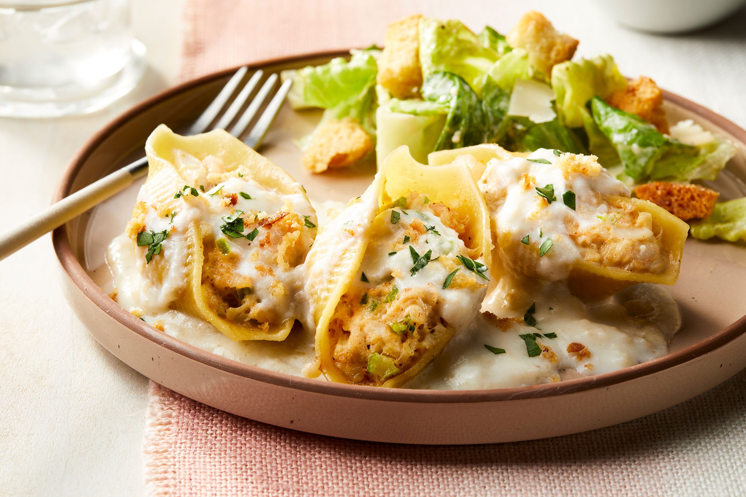 Seafood Stuffed Shells served in a plate with salad on side