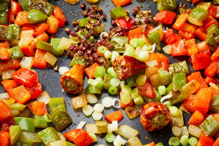 Stirring in whites of the green onion, red chiles and peppercorns. Cooking until fragrant