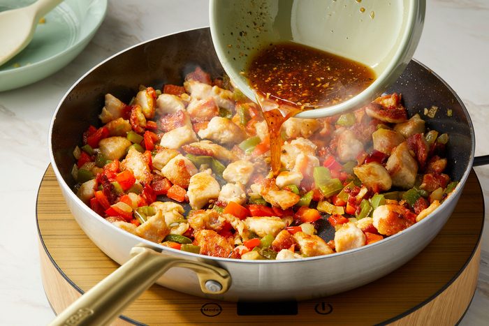 Adding chicken back to the skillet or wok stirring in sauce