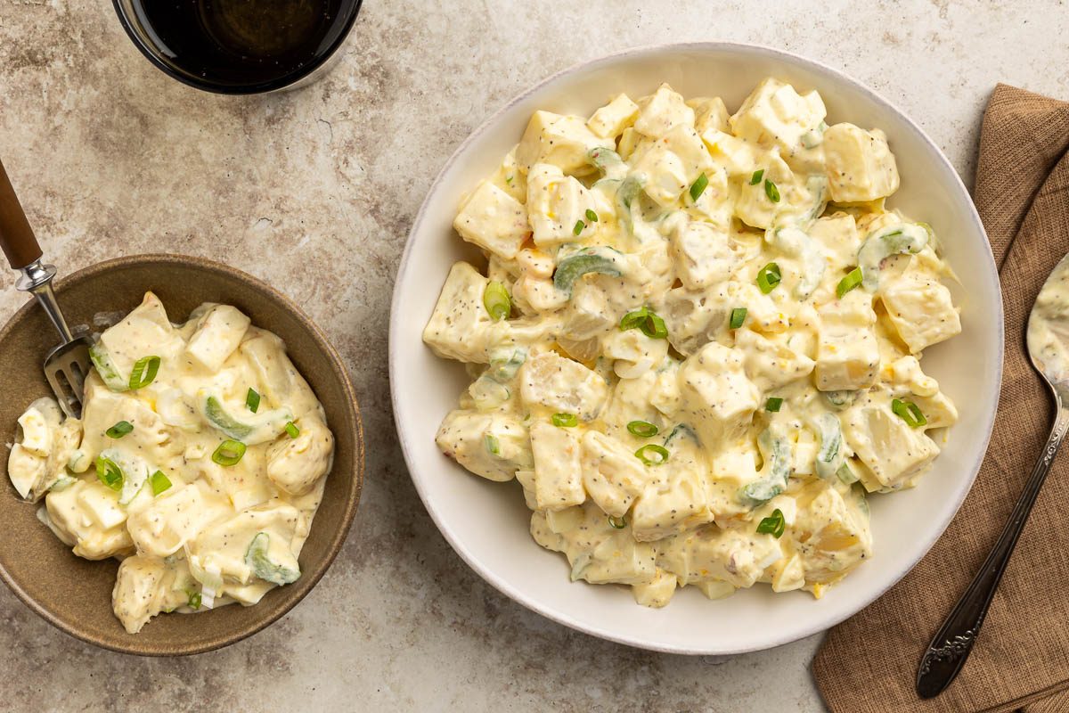 Taste of Home Sour Cream Potato Salad recipe photo of the finished potato salad in serving dish and served in a bowl.
