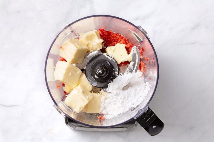Softened butter and confectioners sugar added to the food processor with chopped strawberries for step two of Strawberry Butter recipe for Taste of Home