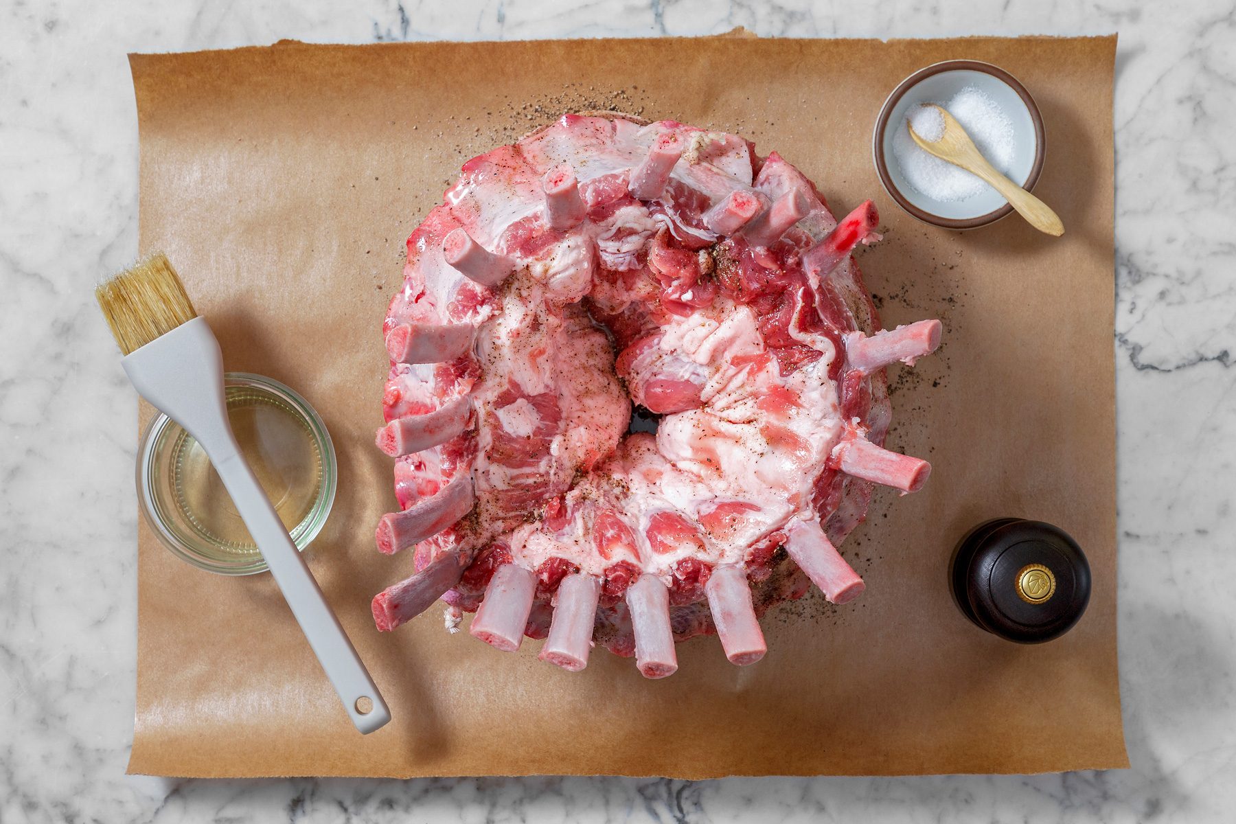 Overhead shot of rub entire roast with 1 teaspoon salt and 1/2 teaspoon pepper; brush 3 tablespoons oil; brush; marble surface.