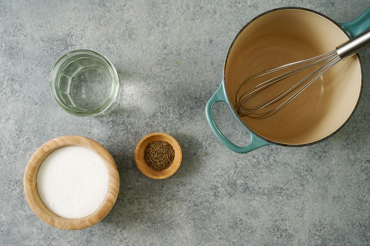 Overhead view of vinegar, sugar, and dried thyme bnext to a Dutch oven, for the Taste of Home Pickled Sweet Onions recipe.