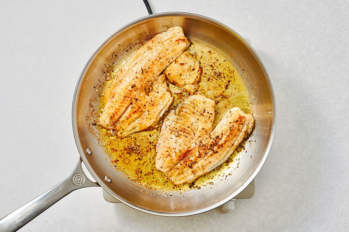 Cooked tilapia fillets in a large skillet