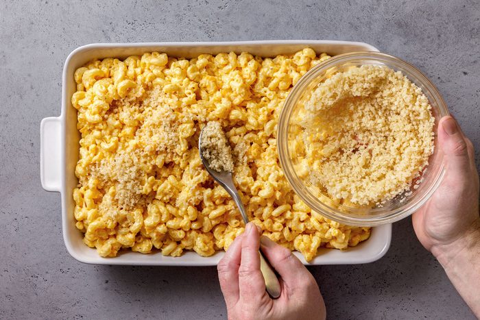 Sprinkling bread crumb mixture on Mac and cheese