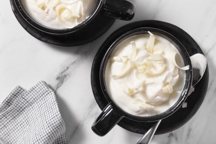 overhead shot of white hot chocolate topped with whipped cream and white chocolates curls