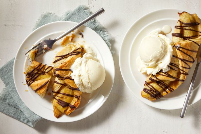 Banana And Chocolate Puff Pastry served in two trays with ice cream and chocolate syrup spread over it