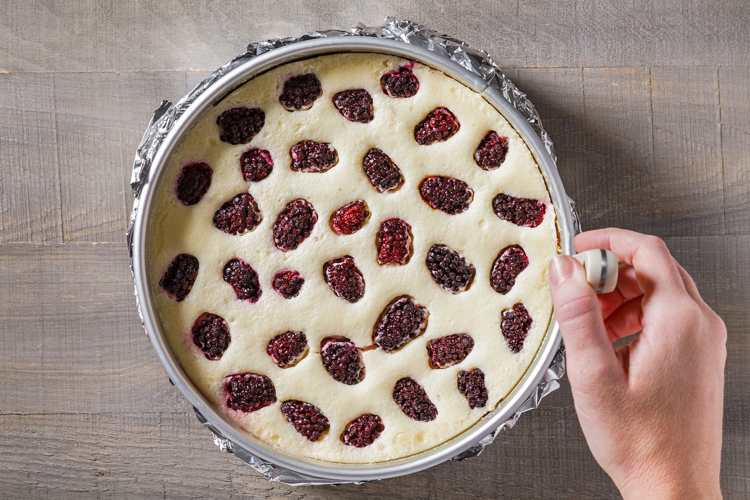 Loosening the sides of baked cheesecake with a knife in pan