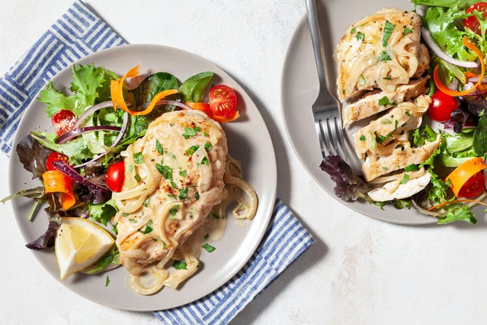 Chicken Dijon served on plates and sprinkled with some parsley with salad on side