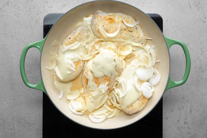 Half and half cream mixture and onions added to roasting chicken breasts in a large skillet