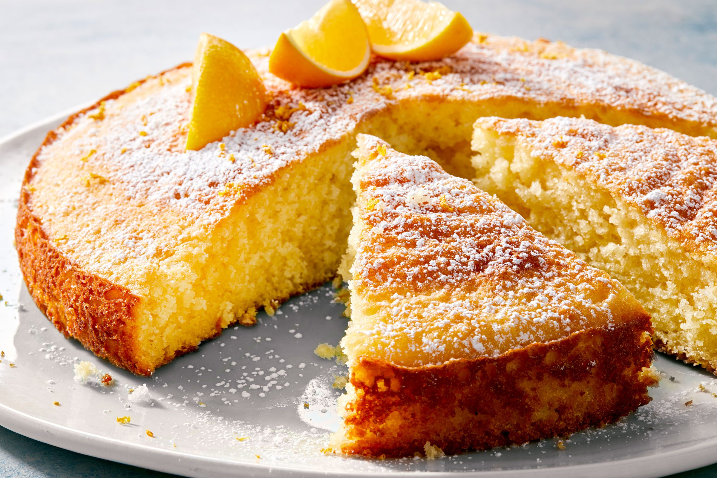 Lemon Olive Oil Cake Bake with lemon slices on it and cut into wedges