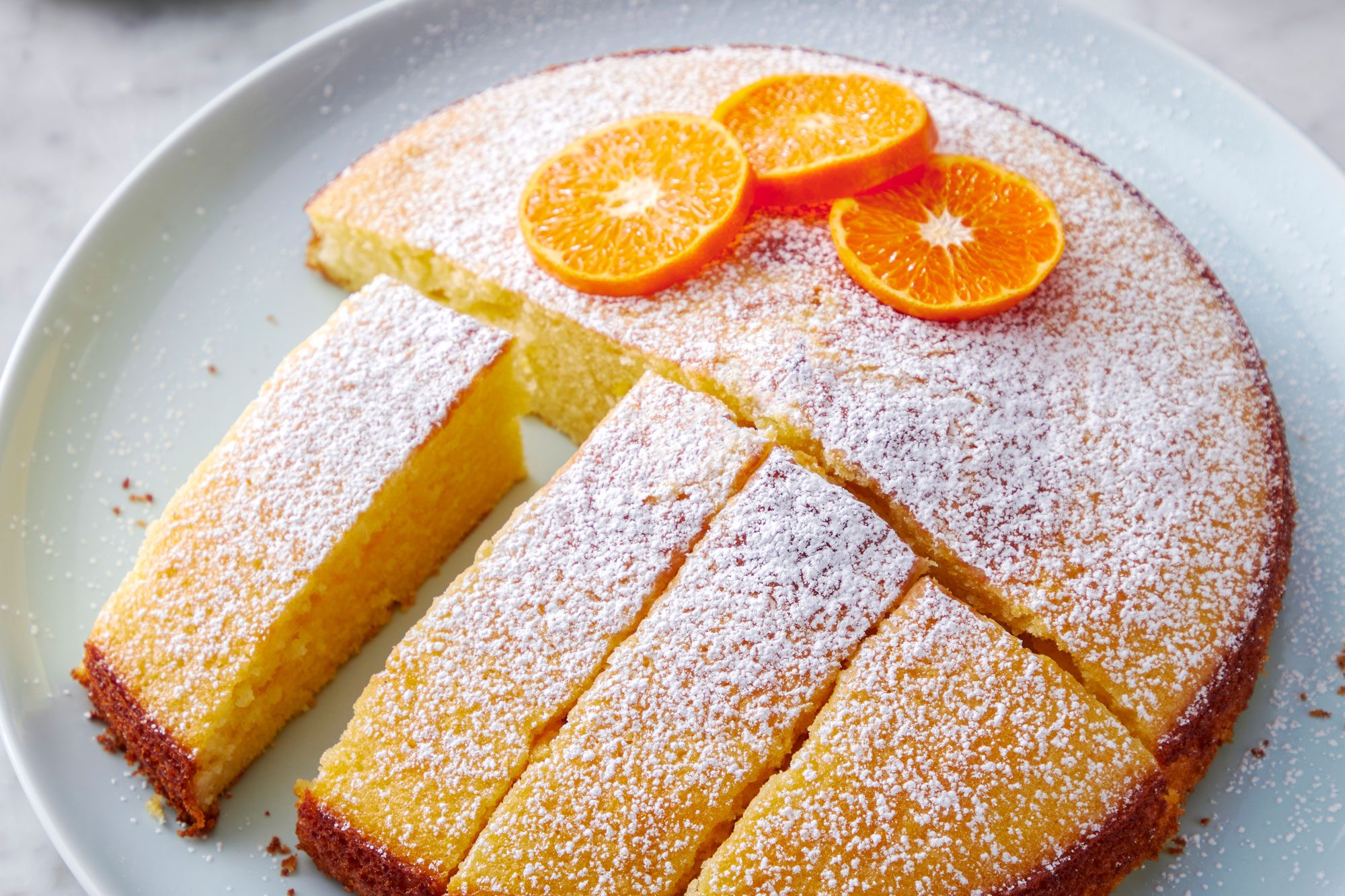 Orange Olive Oil Cake slices served in a plate with sugar sprinkled with orange slices on top