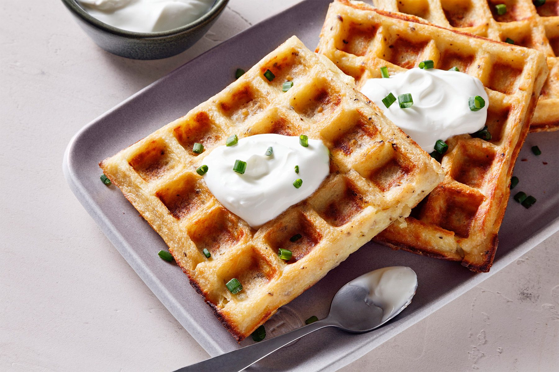 3/4th shot of mashed potato waffles topped with sour cream and minced chives