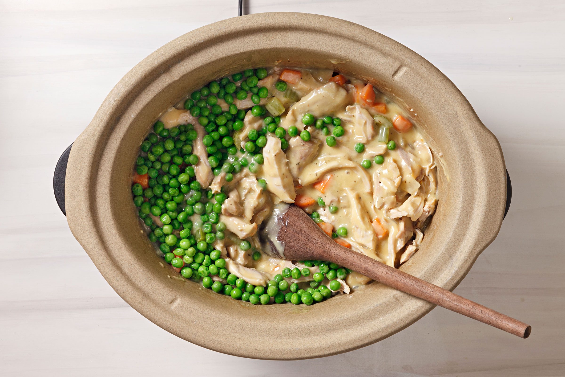 Added peas into chicken and vegetable mixture in a cooker