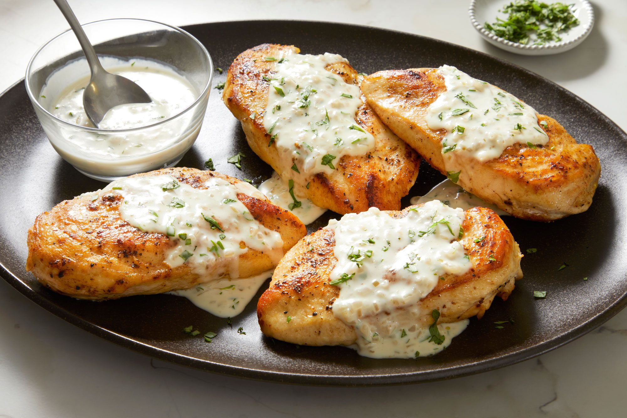 Table view shot of Chicken with Tarragon Sauce; Serve with chicken; Sprinkle with remaining tarragon; spoon; marble surface
