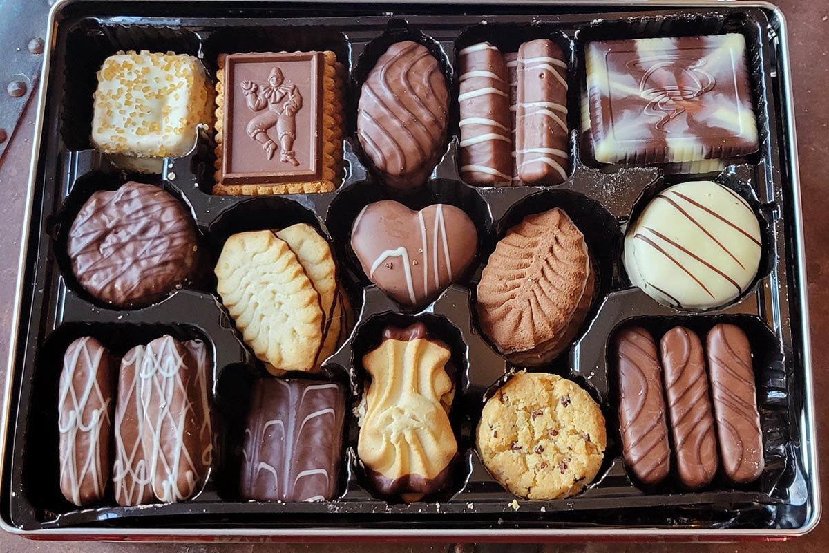 Assorted chocolate and white chocolate cookies arranged in a brown box