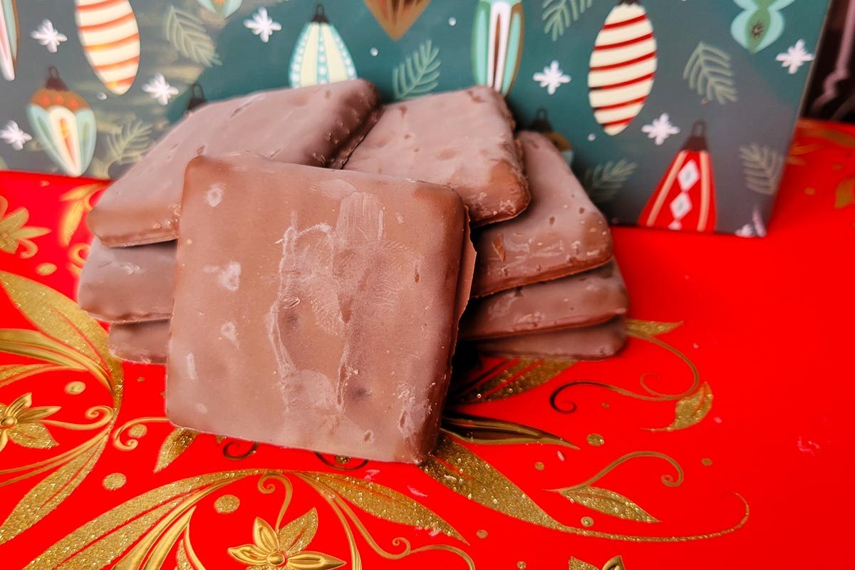 A stack of square, chocolate cookies on a red and green festive holiday background