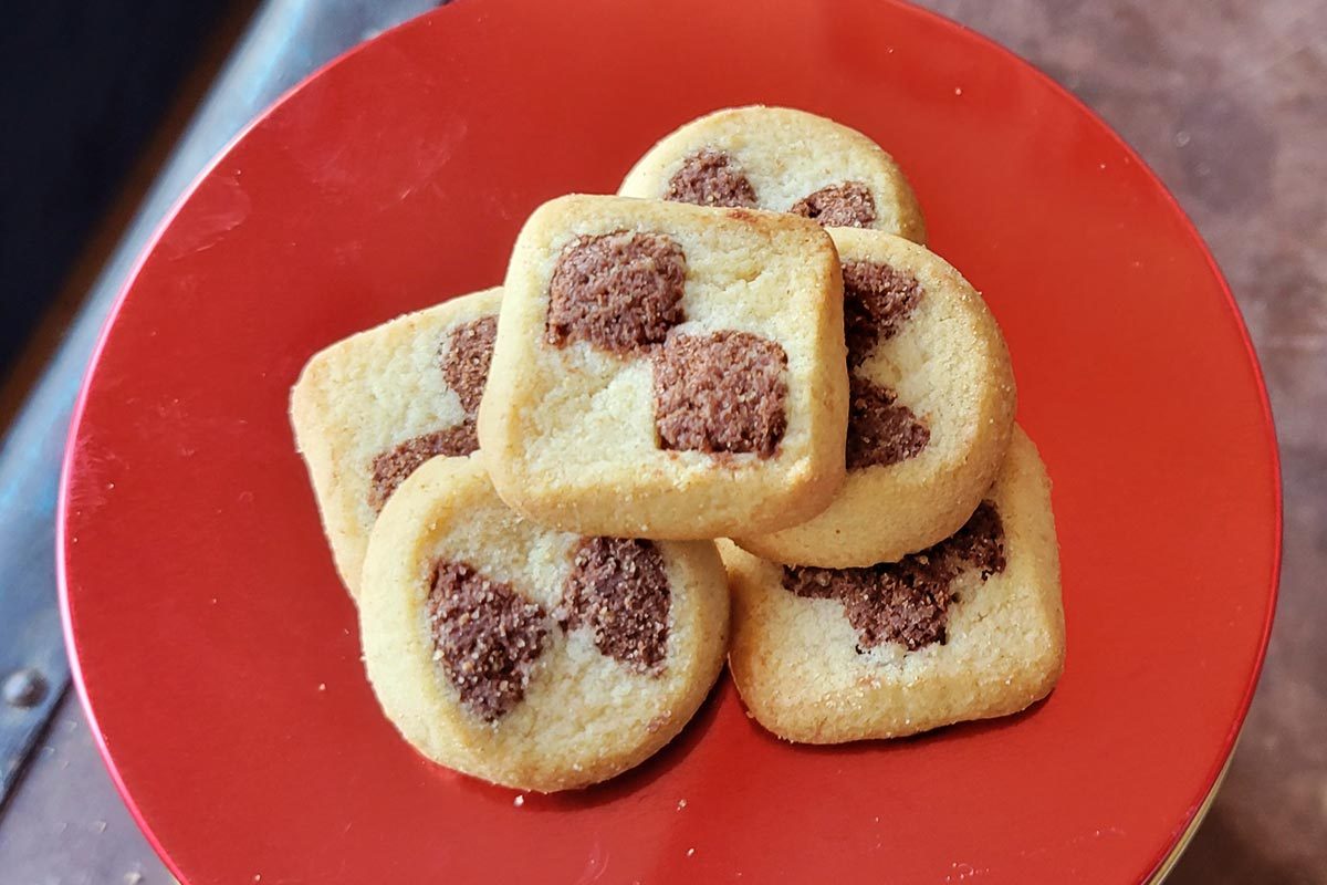 A stack of tan and brown checkered shortbread cookies on a red plate