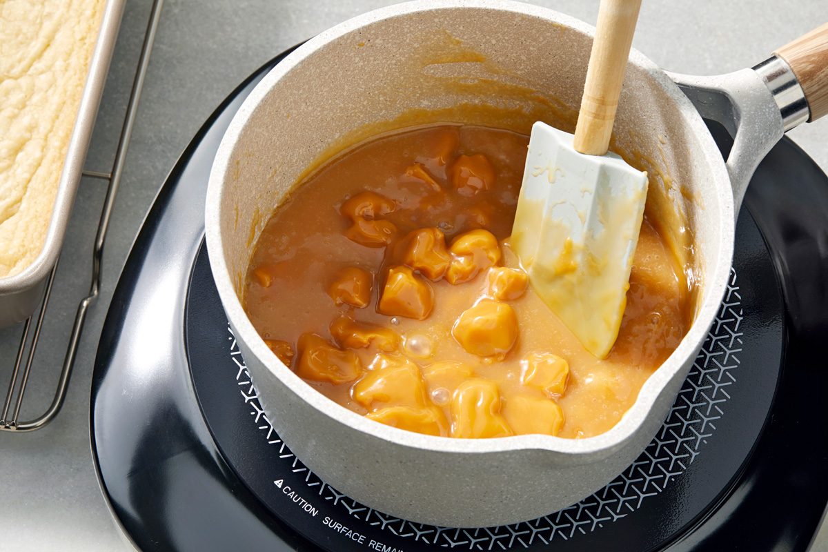 Caramel and cream being melted in a saucepan on heat