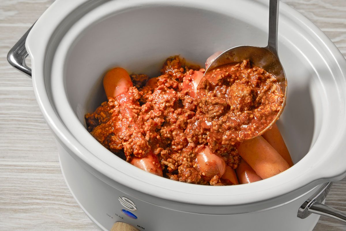 Place hot dogs in a 3-qt. slow cooker; top with beef mixture.