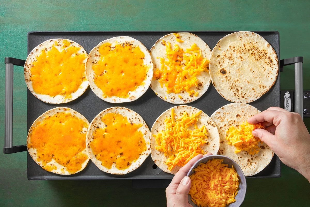 place tortillas on a griddle. Sprinkle 1/4 cup cheddar cheese on each tortilla.