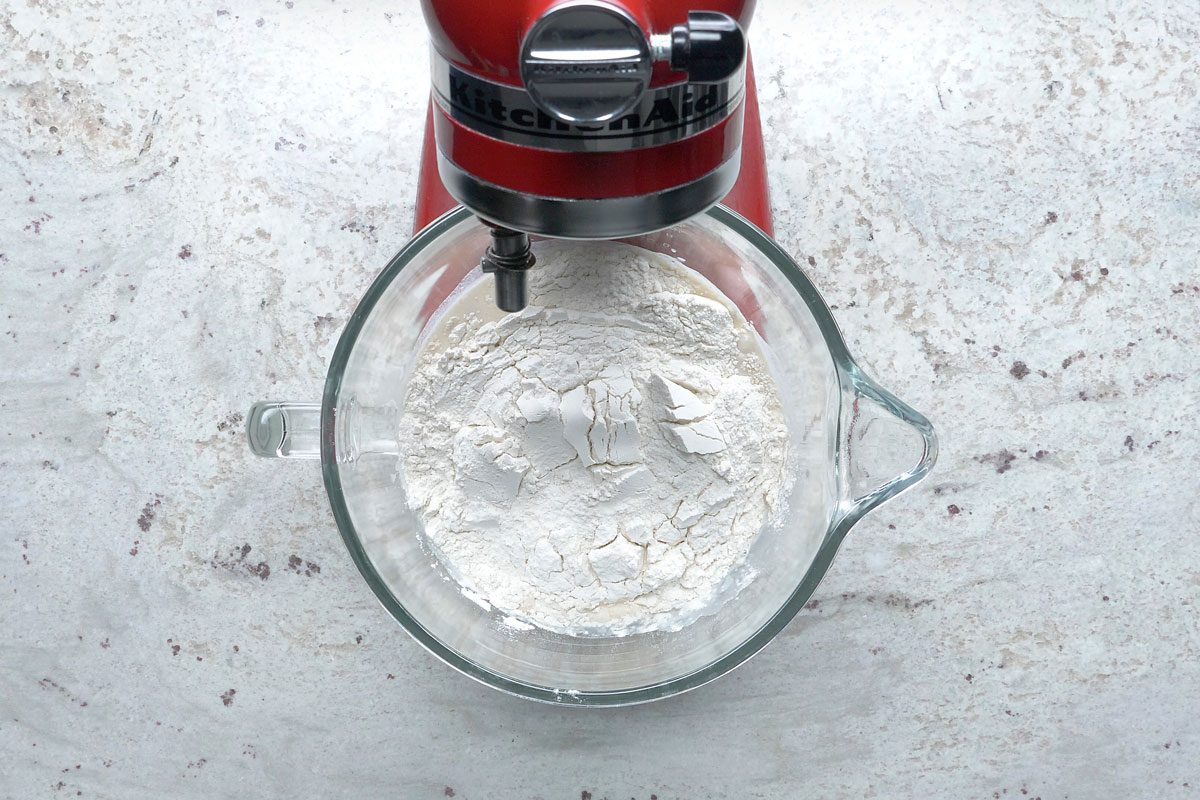 Overhead shot of a large bowl dissolve yeast in warm water; add milk; eggs; butter; sugar; salt and 3 cups flour; beat on medium speed until smooth; stir in enough remaining flour to form a soft dough; marble surface;